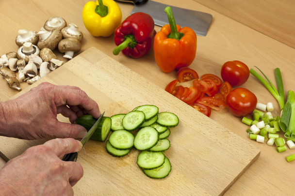 Primo piano di mani di chef che affettano un cetriolo inglese
 - Foto, immagini