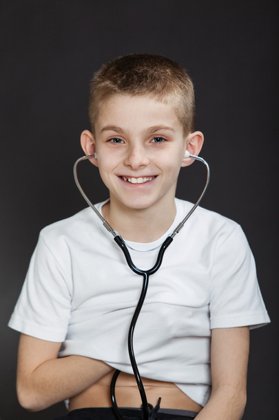 Усміхаючись, хлопчик перевірки його серце з стетоскоп - Фото, зображення
