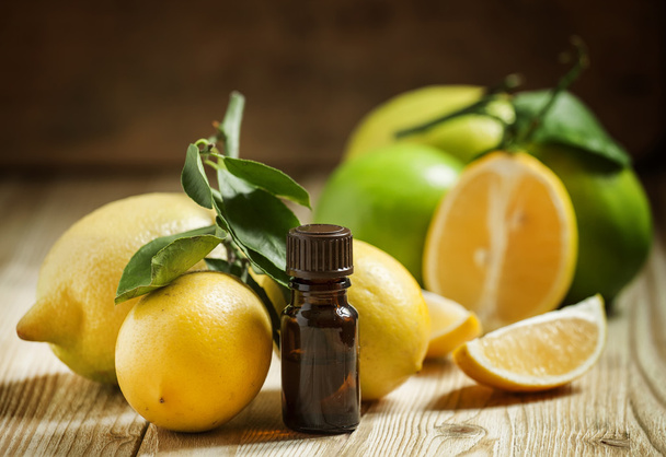 Essential oil of lemon and fresh lemons on the old wooden background  - Фото, зображення