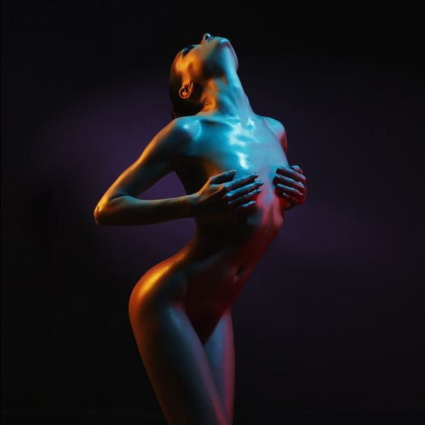 Elegant nude model in the light colored spotlights - Foto, Imagen