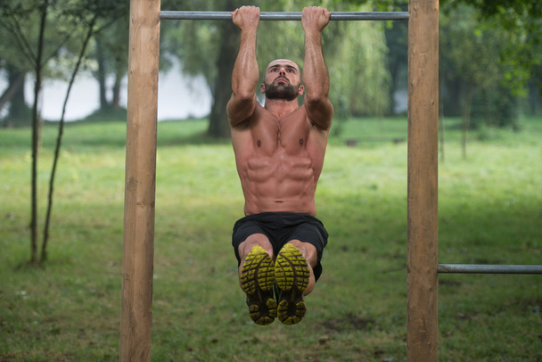 Muscular Man Workout On Bars In Outdoor Gym - Foto, afbeelding