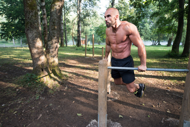 Man Exercising On Parallel Bars Outdoors - Foto, afbeelding