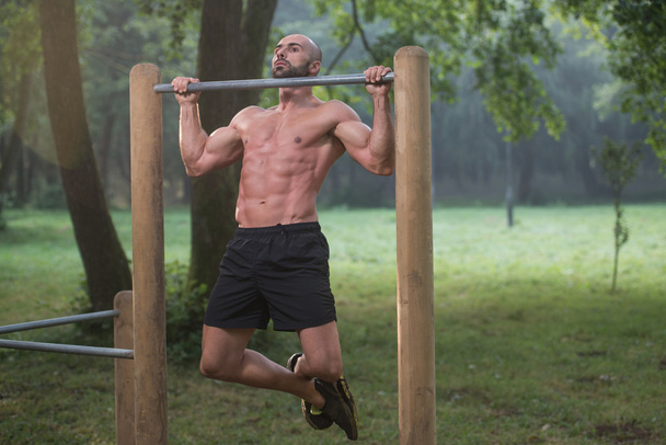 Muscular Man Workout On Bars In Outdoor Gym - Foto, Bild