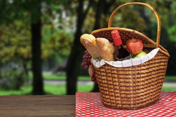 Picknickkorb mit Essen und Trinken auf dem Holztisch - Foto, Bild