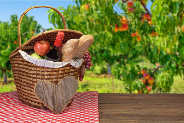 Piknik-kori ruoan ja juoman kanssa puupöydällä
 - Valokuva, kuva