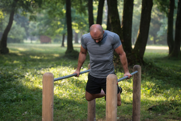 Man Exercising On Parallel Bars Outdoors - Fotografie, Obrázek