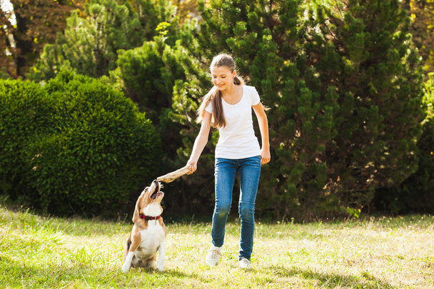 Girl plays with a dog in the yard - Фото, зображення