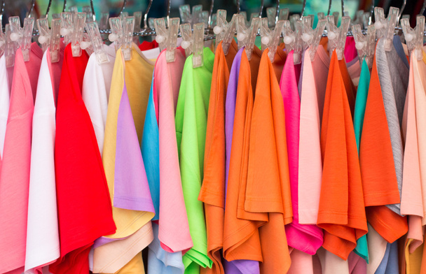 Colorful choice of casual clothes on wooden hangers in the market - Photo, Image