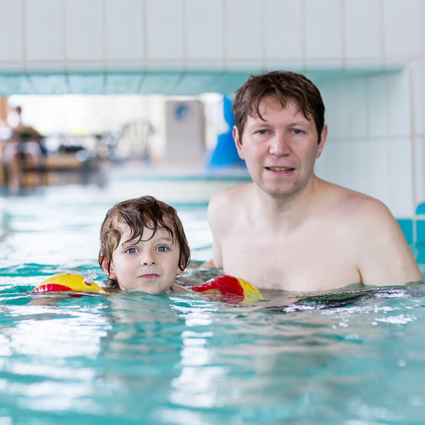 Junger Vater bringt seinem kleinen Sohn das Schwimmen im Haus bei - Foto, Bild