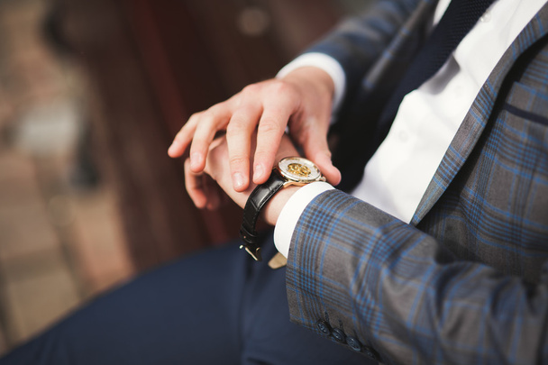 Confident businessman looking on his wrist watch in suit - Fotoğraf, Görsel