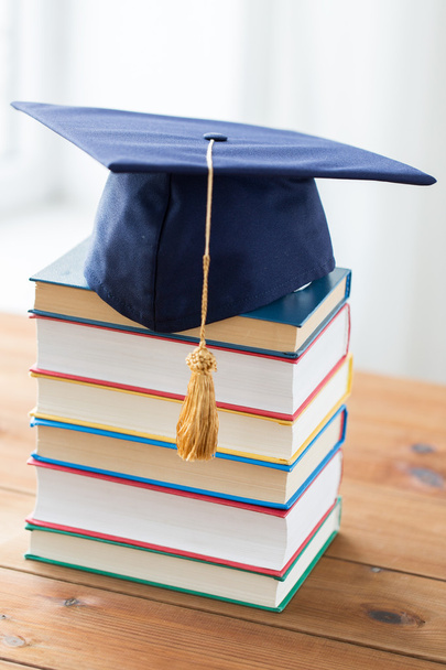 close up of books and mortarboard on wooden table - Фото, зображення