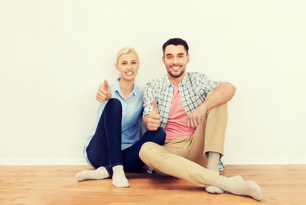 happy couple showing thumbs up at new home - Foto, imagen