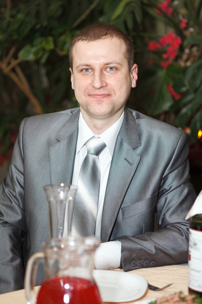 Happy bridegroom sitting at a table of a luxury restaurant - Fotografie, Obrázek