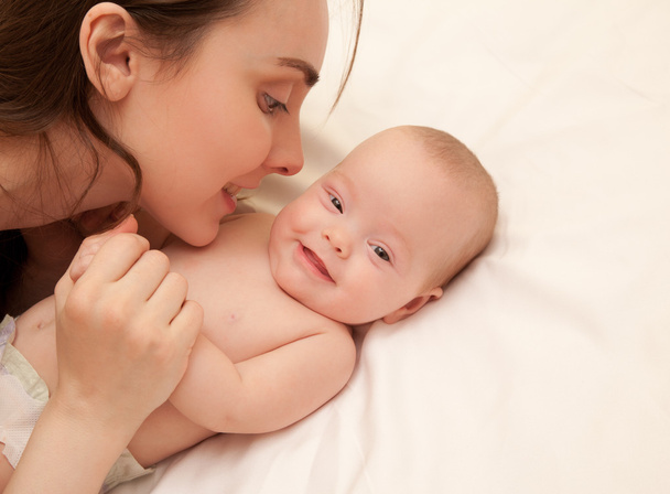 Bild einer glücklichen Mutter mit entzückendem Baby im Bett - Foto, Bild