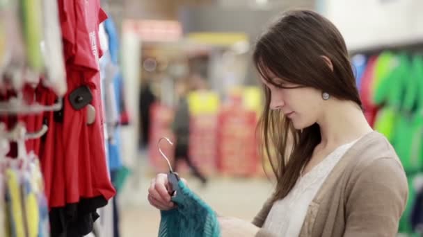 junge Frau wählt Kleidung für ein Kind - Filmmaterial, Video