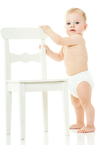 baby holds on to a white chair - Fotó, kép
