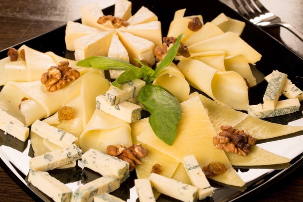 Different types of cheese, on a black plate - Photo, Image