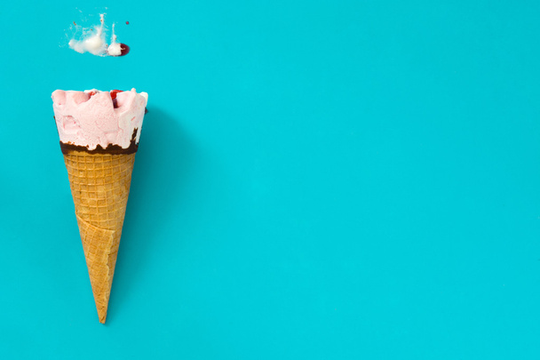 Cono de helado de fresa sobre fondo azul
 - Foto, imagen