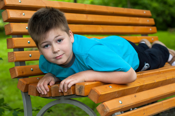 The boy lay on a bench - Фото, изображение