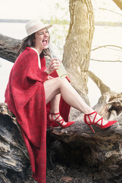 woman sitting on tree with bottle of champagne - Фото, зображення