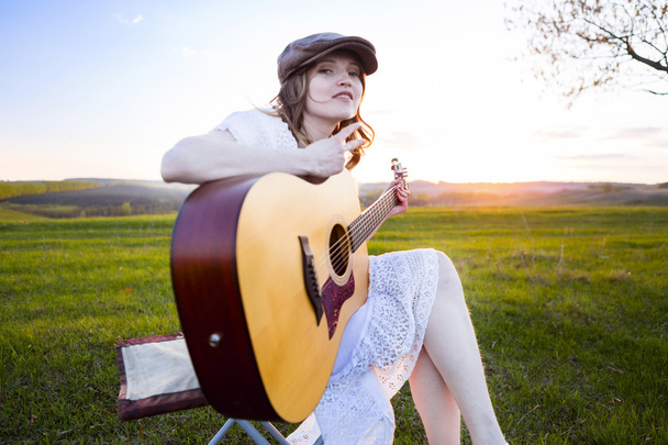 Country  girl sitting with acoustic guitar at field  - Valokuva, kuva