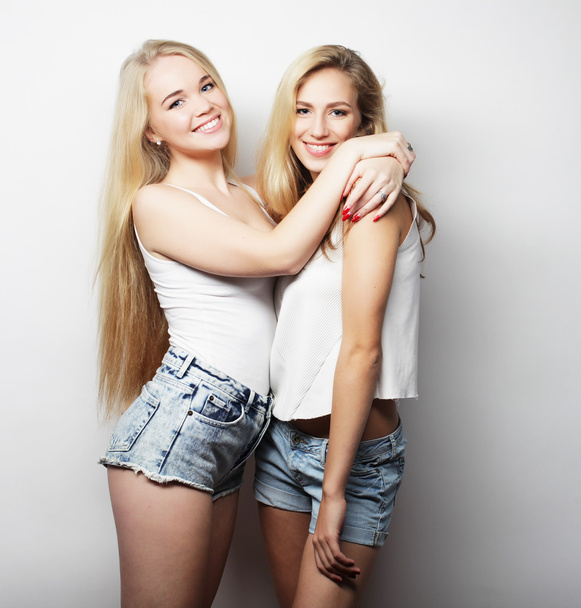 Two young girl friends standing together and having fun - 写真・画像