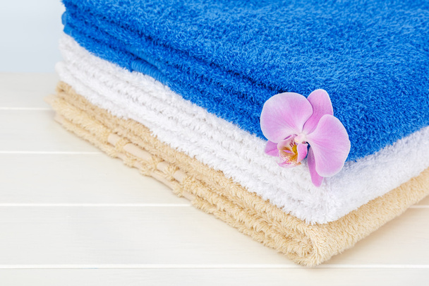 Stack of towels and orchid on a white background. - Foto, immagini