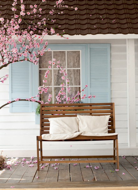 brown wooden bench with pillow near the cherry blossoms - Foto, imagen