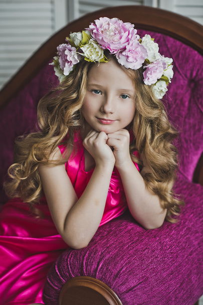 Little girl in a wreath of lilac flowers sitting on the sofa 602 - Φωτογραφία, εικόνα