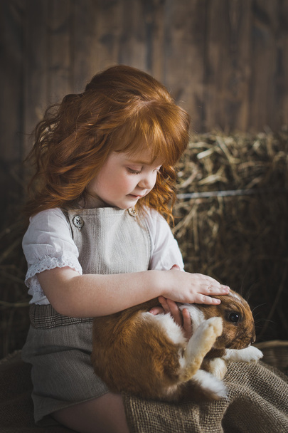 Little girl is playing with a red rabbit 6041. - Foto, imagen