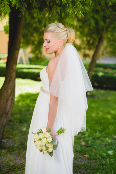 Bride in white dress standing near tree park - Valokuva, kuva
