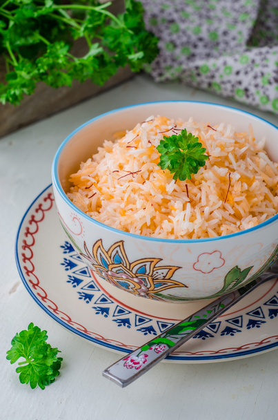 Rice pilaf with saffron in ornament bowl on wooden background. Selective focus - Photo, Image