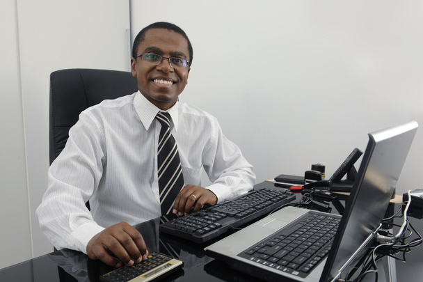 Happy businessman working at desk smiling - Фото, изображение