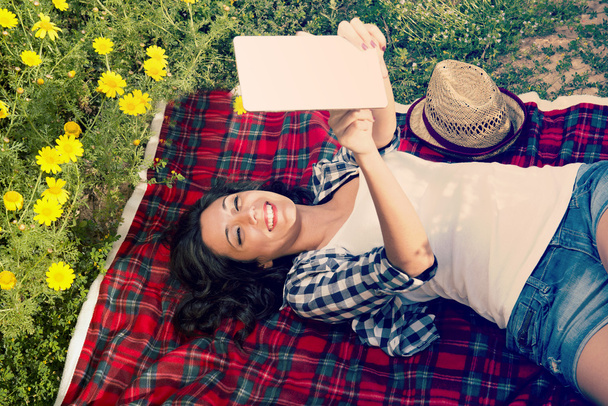glückliches Mädchen beim Lesen eines Tablets auf einer Decke - Foto, Bild
