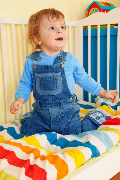 Happy toddler sitting in the baby cot - 写真・画像