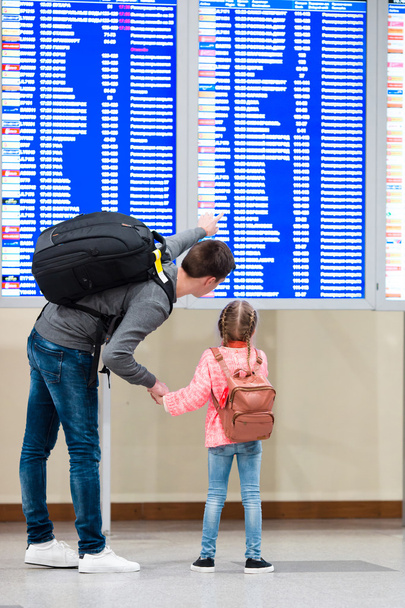 Little girl with her father background flight information at airport - Φωτογραφία, εικόνα
