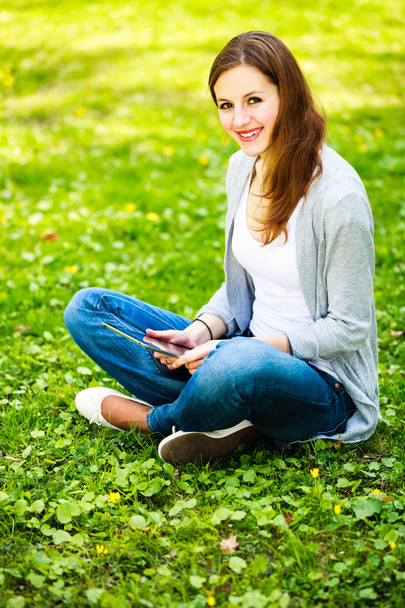 Young woman using her tablet computer while relaxing outdoors - Foto, Imagem