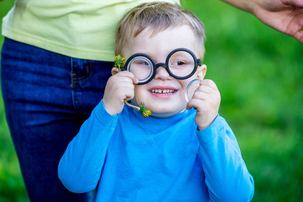 Gelukkig babyjongen dragen bril tegen een achtergrond van de natuur - Foto, afbeelding