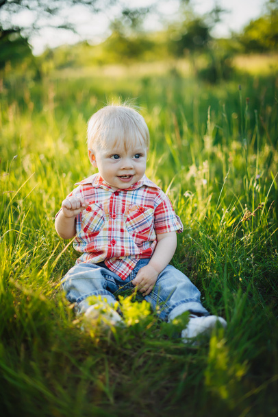 Niño sentado en la hierba
 - Foto, imagen