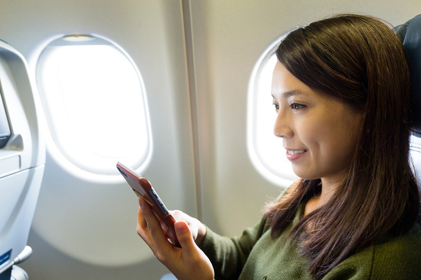Femme utilisant un téléphone portable à l'intérieur de l'avion
 - Photo, image