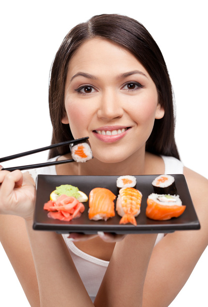 Young attractive woman holding sushi with a chopsticks - 写真・画像