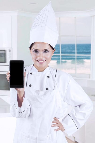 Female chef shows empty screen smartphone - Foto, afbeelding