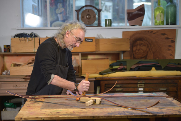 Leather goods craftsman at work in his workshop - Фото, изображение