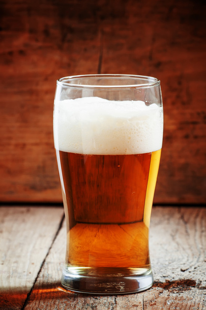 large glass of light beer with foam on the old wooden background  - Foto, Bild