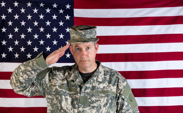 男性ベテラン兵士の背景にアメリカの国旗に敬礼  - 写真・画像