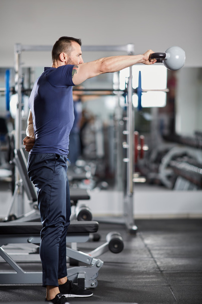 Man doing shoulder workout with kettle  - Photo, Image