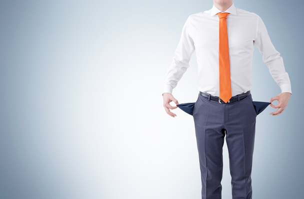 Unemployment concept with businessman showing empty pockets on grey background. - Fotografie, Obrázek