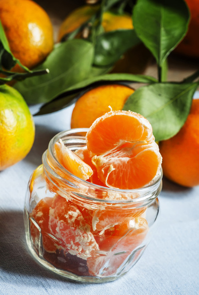 Ripe juicy peeled tangerines in a glass jar on a blue napkin  - Фото, зображення