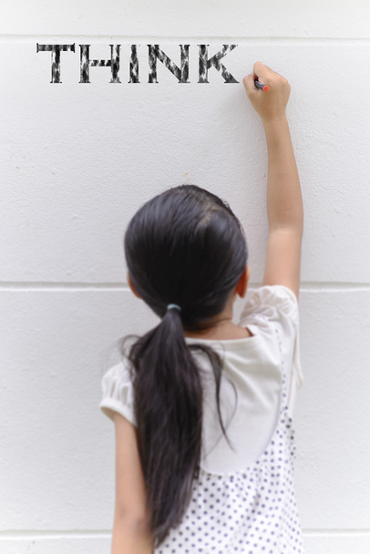 Kid writing think word on wall with her black pencil - Zdjęcie, obraz