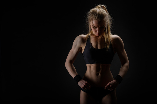 Young muscular woman posing on black - Photo, Image